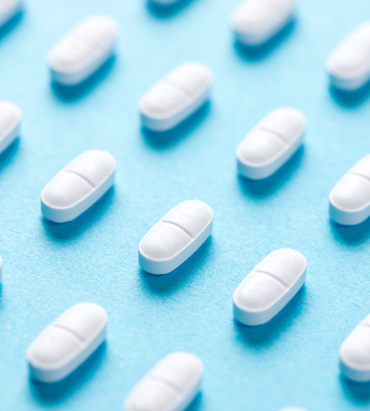 White pills on a pale-blue surface